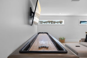 A billiards table in a modern room with a view of a wooden deck through a window. - Shangri-la - Bean Point - Rooftop Pool -golf Cart (Anna Maria)