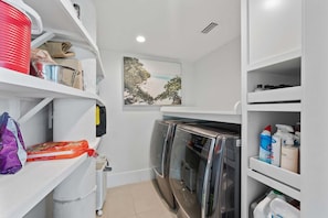 A laundry room with stacked laundry, a washing machine, and a dryer. - Shangri-la - Bean Point - Rooftop Pool -golf Cart (Anna Maria)