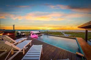 A poolside area with lounge chairs and a decorative flamingo float. - Shangri-la - Bean Point - Rooftop Pool -golf Cart (Anna Maria)