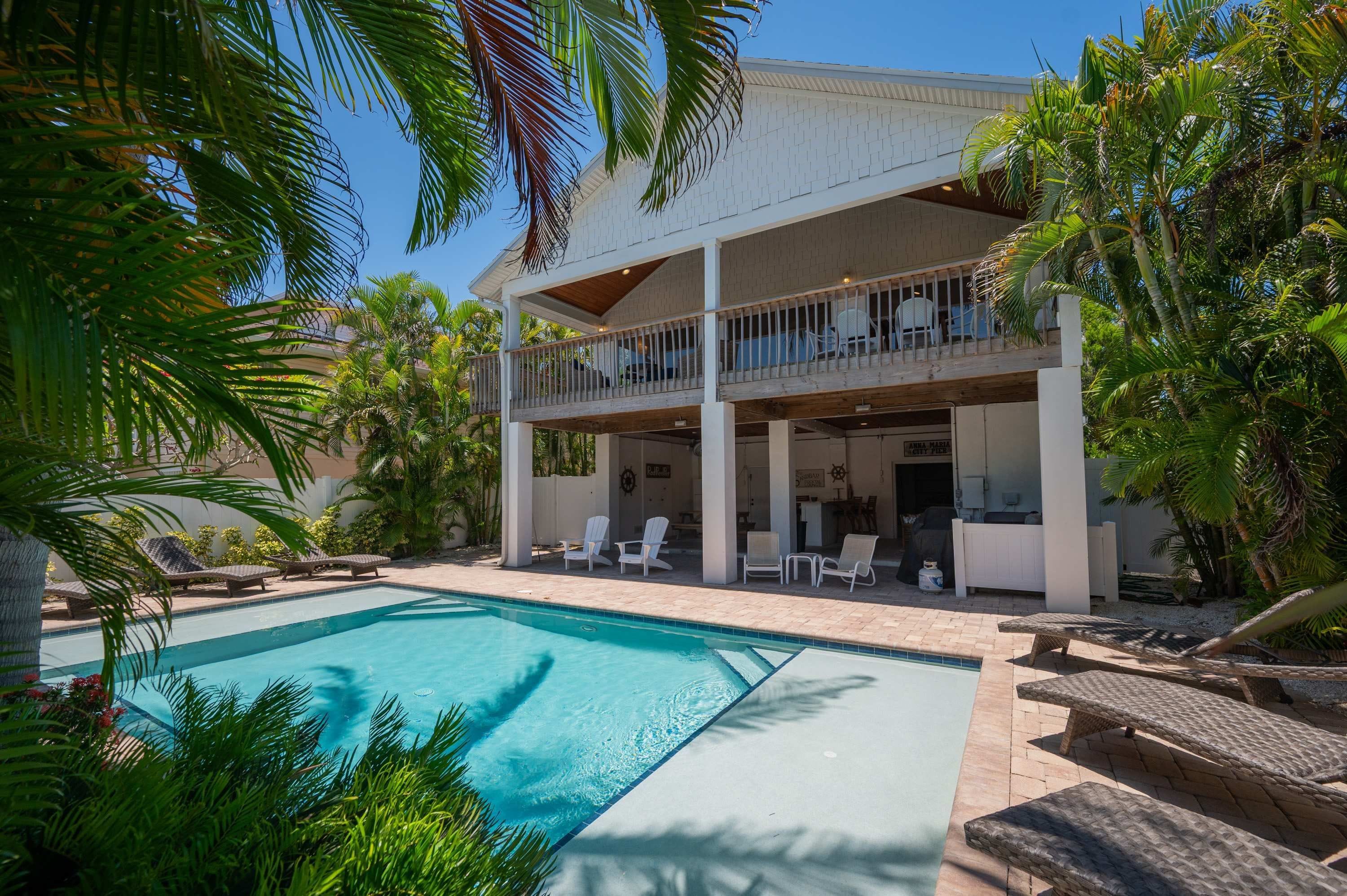 A two-story building with a pool, outdoor seating, and a covered patio area.