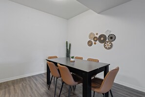 Un comedor con una mesa rectangular, seis sillas y una planta de cactus sobre la mesa.