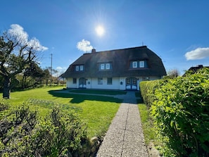A large house with a thatched roof, a paved driveway, and a well-maintained lawn. - House Hochstieg Holiday Apartment 3 (Nieblum)