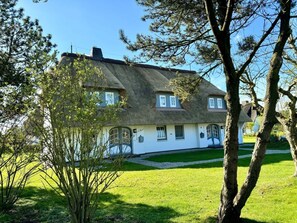 A traditional house with a thatched roof, multiple windows, and a well-maintained lawn. - House Hochstieg Holiday Apartment 3 (Nieblum)