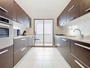 A modern kitchen with stainless steel appliances, a built-in oven, and a large window. - Palmeira Apartment by Atlantic Holiday (Santa Cruz)