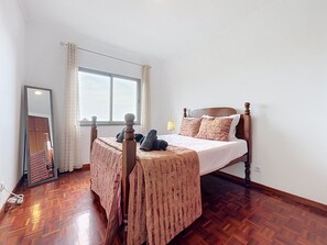 Una camera da letto con un letto di legno, uno specchio, una finestra e una lampada.