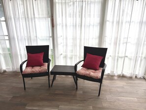 Two wicker chairs with red cushions and a small table in a room with wooden flooring and white curtains. - Beautiful 4 bedroom home on the bike trail and east of Rt 1! (Lewes)
