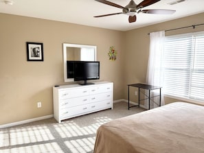 A bedroom with a bed, a TV on a dresser, a ceiling fan, and a window with blinds. - Beautiful 4 bedroom home on the bike trail and east of Rt 1! (Lewes)