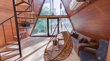 A wooden interior with a hanging chair, a sofa, and a staircase.