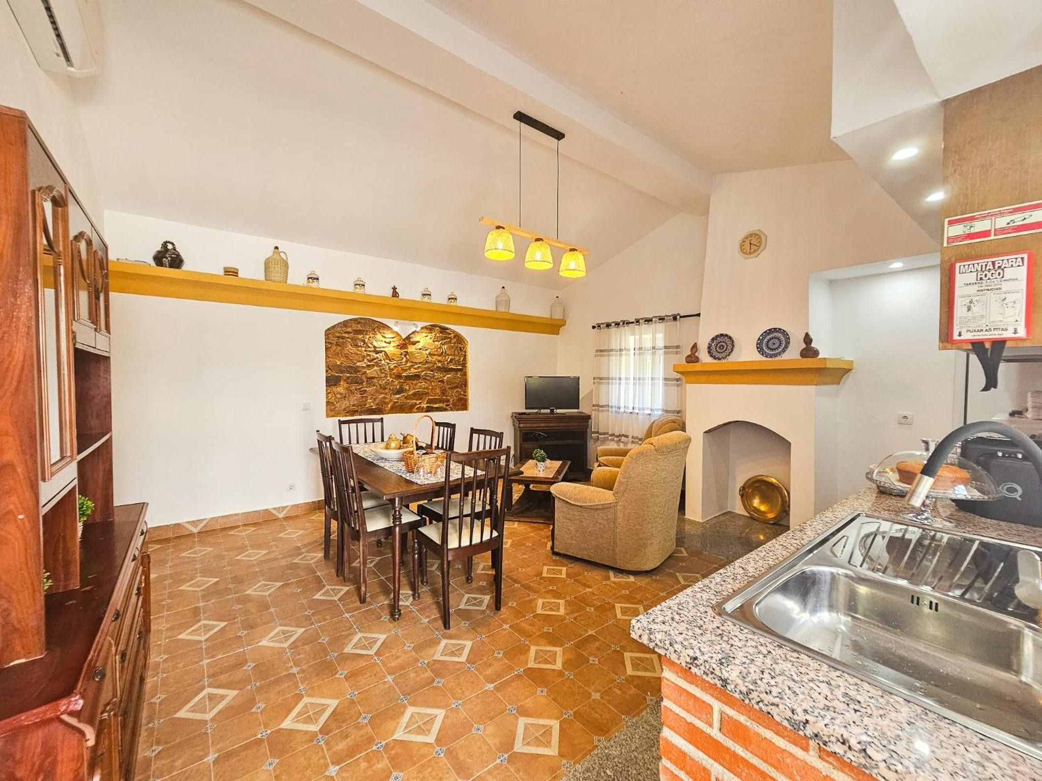 A kitchen with a dining table, chairs, a sofa, a fireplace, and a sink.