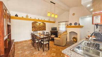 A kitchen with a dining table, chairs, a sofa, a fireplace, and a sink.