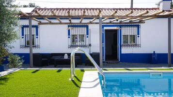 Un edificio residencial con piscina, terraza techada y césped cuidado.