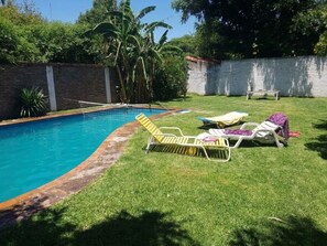 A swimming pool with a brick border, surrounded by a grassy lawn with lounge chairs. - New Listing (Monte Grande)