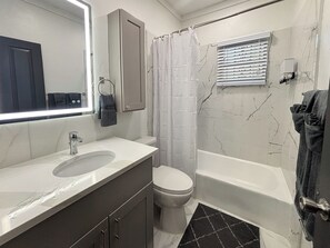 Une salle de bain avec un lavabo, des toilettes et une baignoire, le tout de couleur blanche.