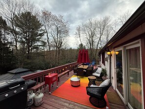 Eine Terrasss mit Grill, Sitzgruppe und einem roten Sonnenschirm.