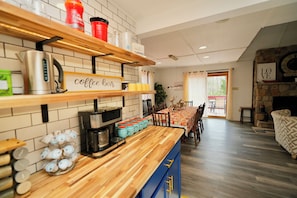 Eine Küche mit einer Kaffeebar, einem Essbereich mit Tisch und Stühlen sowie einem Kamin.