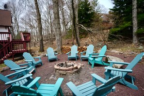 A fire pit surrounded by Adirondack chairs in a wooded outdoor area. - TheGoodTimes House! Hot Tub+GameRoom+petsok! (Lake Harmony)