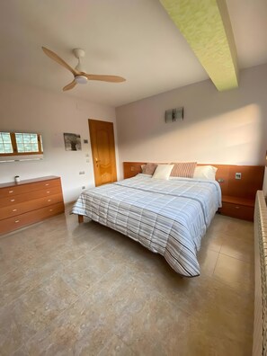 A bedroom with a bed, a wooden dresser, a ceiling fan, a window, and a door. - Apartment 'Ca La Cabrera' with Mountain Views, Private Terrace and Wi-Fi (Alfara de Carles)