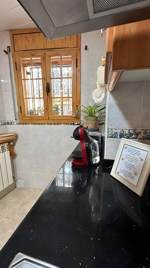 A kitchen with a black countertop, a kettle, a potted plant, and a window with a view. - Apartment 'Ca La Cabrera' with Mountain Views, Private Terrace and Wi-Fi (Alfara de Carles)