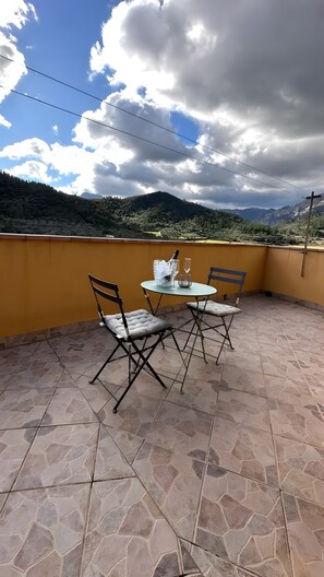 A patio with a table and chairs, a bottle of champagne, and a glass. - Apartment 'Ca La Cabrera' with Mountain Views, Private Terrace and Wi-Fi (Alfara de Carles)