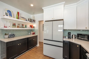 A modern kitchen with white cabinetry, a double-door refrigerator, a microwave, and a coffee maker. - Hauser House l Artful Spanish-Style Bungalow (Los Angeles)