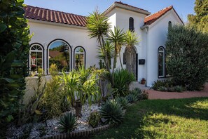 A building with a white facade, red-tiled roof, and arched windows. - Hauser House l Artful Spanish-Style Bungalow (Los Angeles)