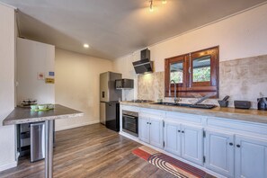 A compact kitchen with a built-in oven, a microwave, and a stainless steel refrigerator. - Kaz Barouty - Vue mer et Le Port - Clim (La Possession)