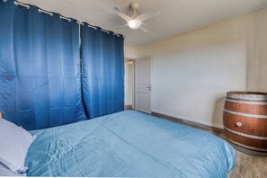 A bedroom with a bed, a ceiling fan, a door, and a wooden barrel. - Kaz Barouty - Vue mer et Le Port - Clim (La Possession)