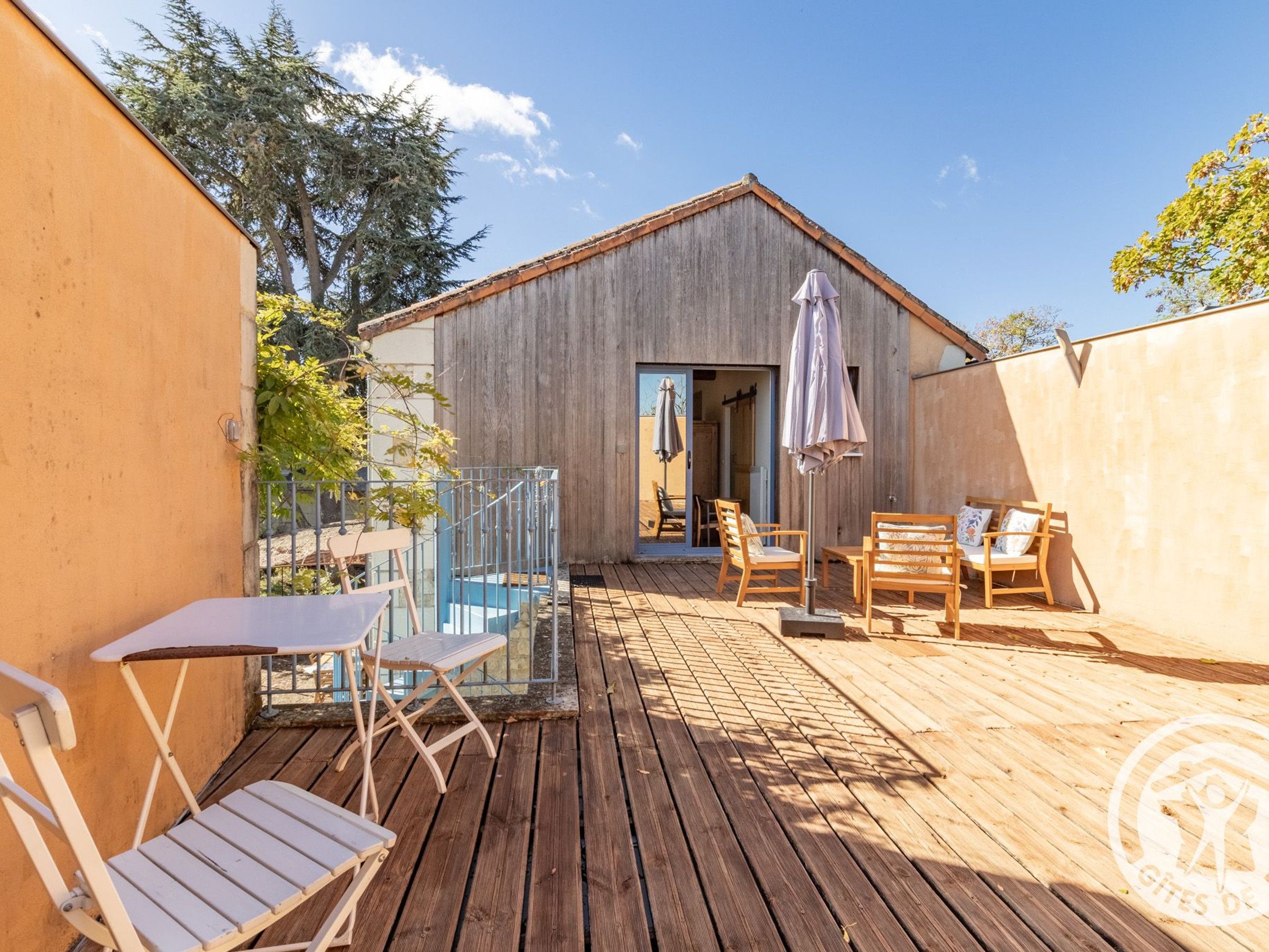 A wooden deck with outdoor furniture, a small building with a door, and a clear sky.