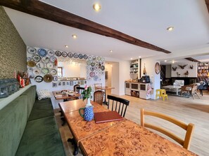 A dining area with a wooden table, chairs, and a wall decorated with plates. - House with private pool - 13 guests (Montchal)