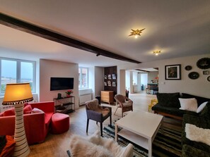 A modern living room with a flat-screen TV, red and black sofas, a coffee table, and a fireplace. - House with private pool - 13 guests (Montchal)