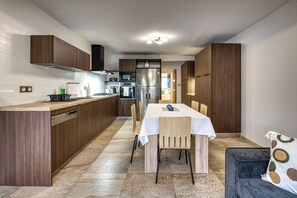 A modern kitchen with wooden cabinets, a dining table, and a sofa. - Ti'Bulle - Petfriendly - Jacuzzi (Saint-Pierre)