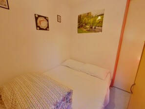 A bedroom with a bed, a pillow, a wall-mounted picture, and a door. - Apartment near shops - 4 guests (Prémanon)
