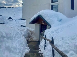 A snow-covered entrance to a building with a wooden staircase leading up to a door marked 'Bât.A'. - Plein Soleil - Balcon - Proche pistes (Hauteluce)