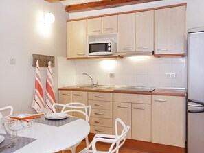 A compact kitchen with a microwave, sink, and wooden cabinets. - Central Barcelona Apartment 2 Bedrooms, near Ramblas (Barcelona)