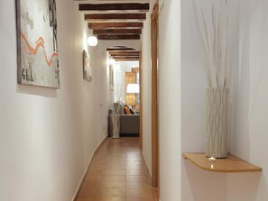 A hallway with a wooden ceiling, a white wall with a framed artwork, and a vase with tall, thin branches on a shelf. - Central Barcelona Apartment 2 Bedrooms, near Ramblas (Barcelona)
