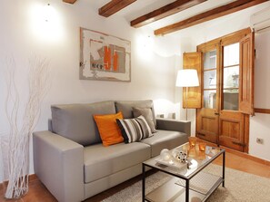 A living room with a grey sofa, a glass coffee table, a lamp, and a wooden door. - Central Barcelona Apartment 2 Bedrooms, near Ramblas (Barcelona)