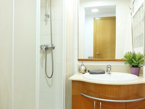 Ein Badezimmer mit Dusche, Waschbecken, Spiegel und einer Topfpflanze.