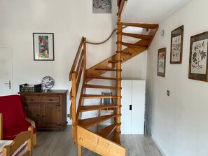 A wooden spiral staircase in a room with a white door, wooden furniture, and framed botanical illustrations on the walls. - Family duplex, pets welcome, parking - 6 guests (Brides-les-Bains)