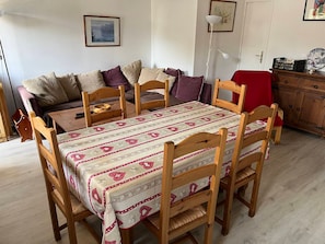 A dining area with a table set for six, surrounded by wooden chairs with cushioned seats. - Family duplex, pets welcome, parking - 6 guests (Brides-les-Bains)