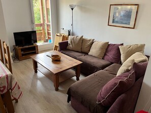 A living room with a sofa, a wooden coffee table, a television on a stand, and a painting on the wall. - Family duplex, pets welcome, parking - 6 guests (Brides-les-Bains)
