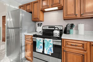 Una cocina con armarios de madera, un refrigerador de acero inoxidable, una estufa y un microondas.