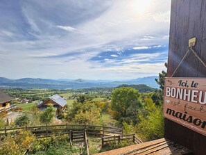 A wooden sign with text, a wooden fence, and a view of a house and landscape. - Cosy studio with south balcony - 2 guests (Saint-Michel-de-Chaillol)