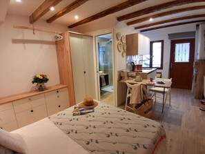 A bedroom with a bed, bedside table, and a wardrobe. There is a kitchen area with a stove, sink, and cabinets. - Charming studio in the heart of Bouzigues (Bouzigues)