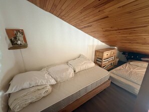 A bedroom with a loft bed, a wooden dresser, and a wall-mounted shelf with a picture. - Duplex apartment with mountain view - 6 guests (Plagne Villages)