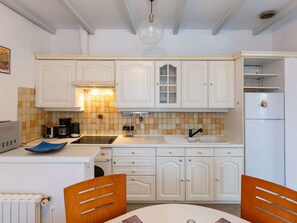 A kitchen with white cabinets, a black countertop, a sink, and a refrigerator. - Bright apartment, mountain views - 4 guests (Argelès-Gazost)