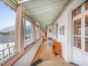 Ein Korridor mit Holzboden, ein Essbereich mit Stühlen und Tisch, große Fenster und Blick auf einen Berg.