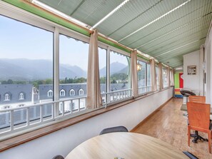 A room with a large window, a wooden table, and a chair. - Bright apartment, mountain views - 4 guests (Argelès-Gazost)