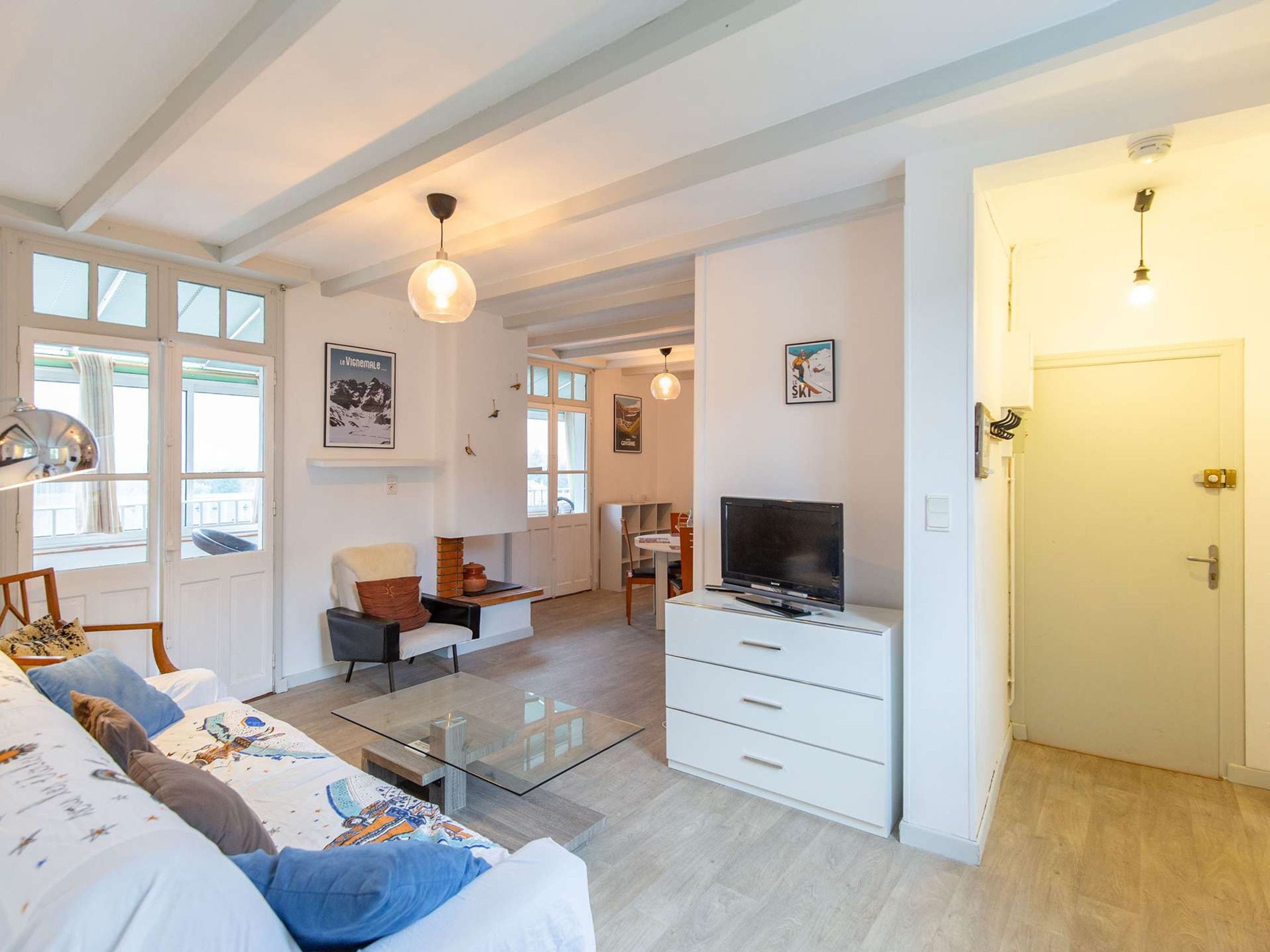 A modern living room with a sofa, coffee table, TV, and a door leading to another room.