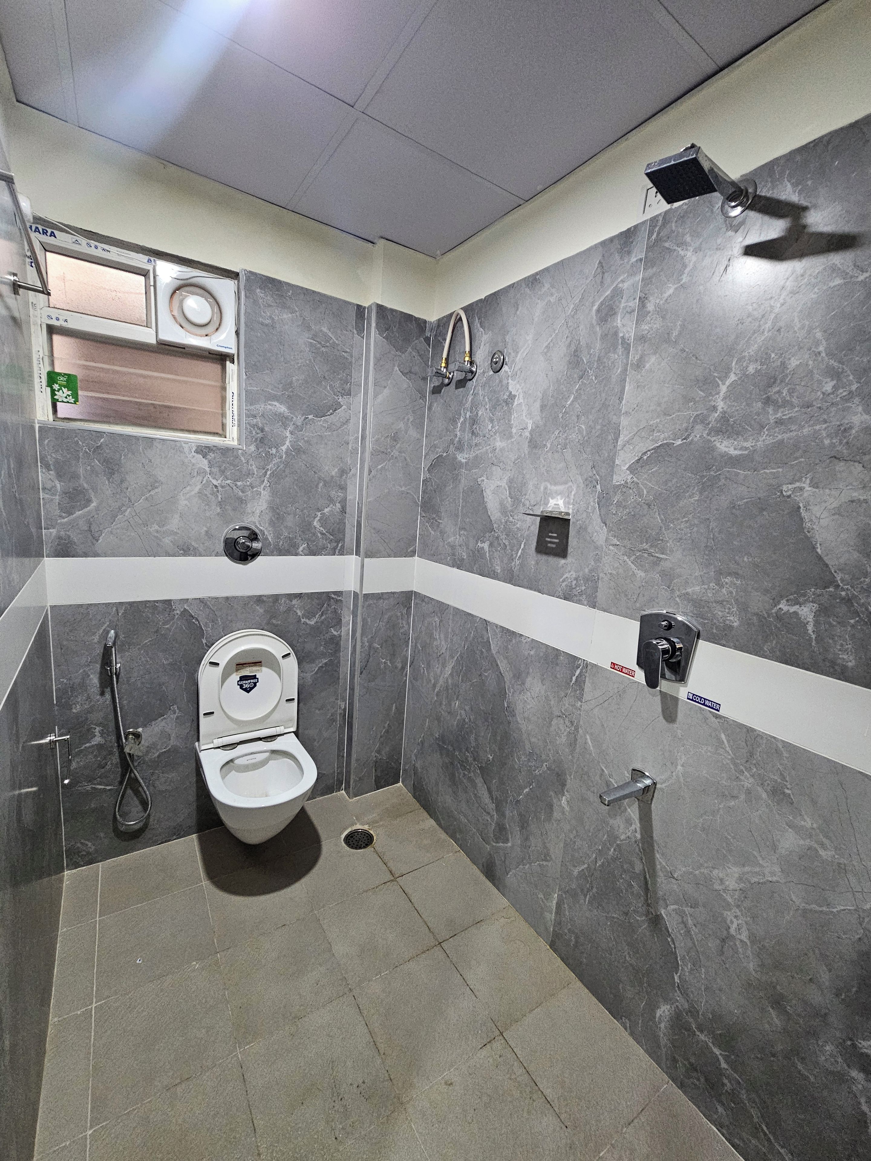 Un baño con inodoro, ducha y panel de control de temperatura.