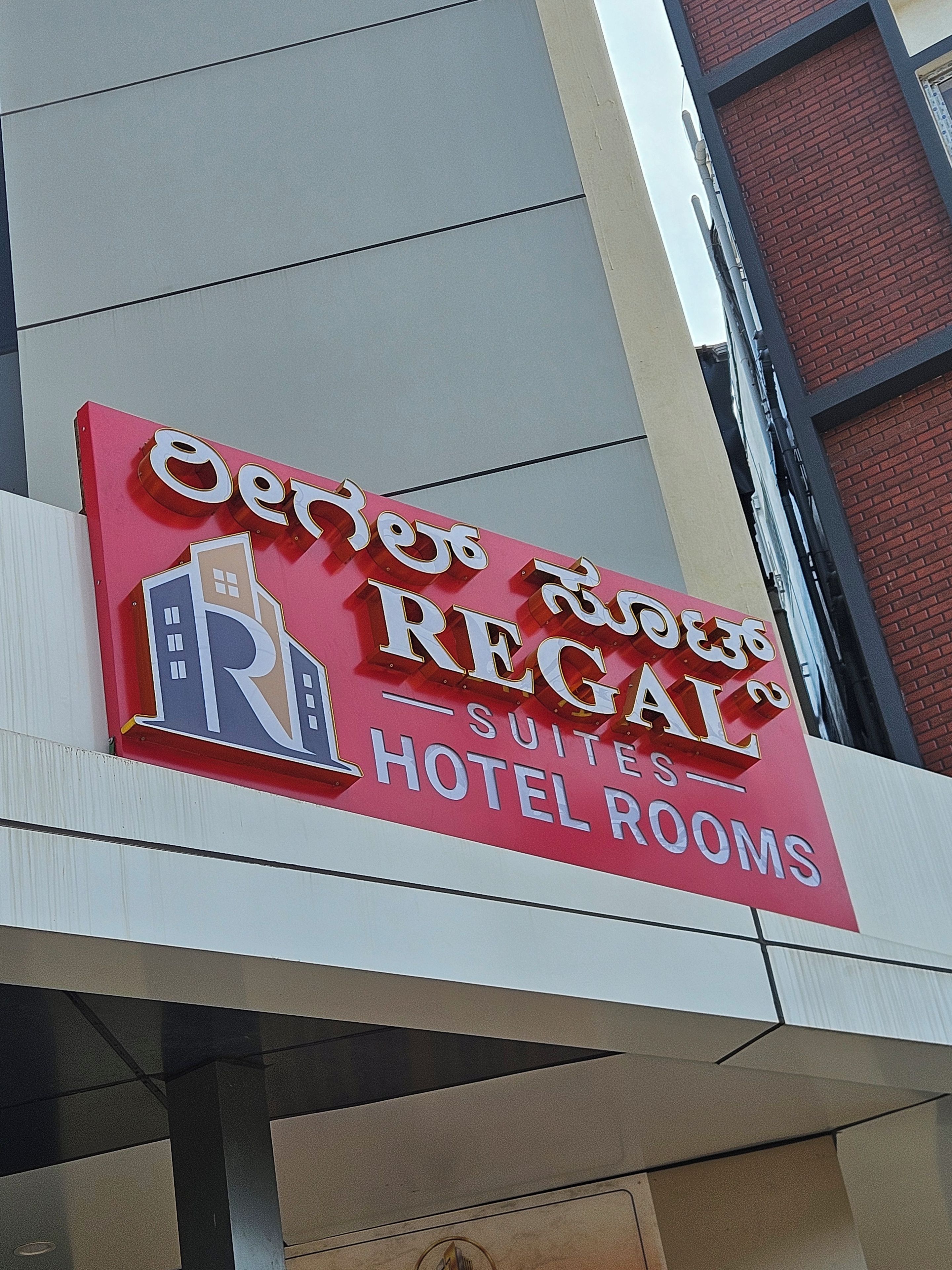 A hotel sign with the name 'Regal Suites Hotel Rooms' in English and another language.